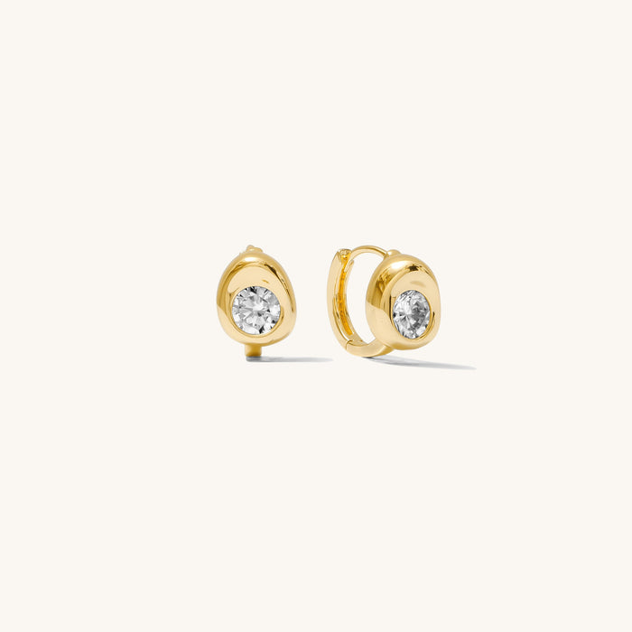 Close up of stone accented gold earrings on a white background