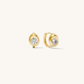 Close up of stone accented gold earrings on a white background