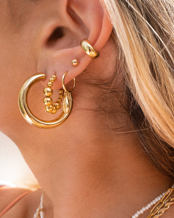 Close-up of an ear with multiple gold earrings