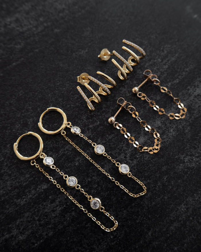 Three pairs of statement earrings on a dark marble background