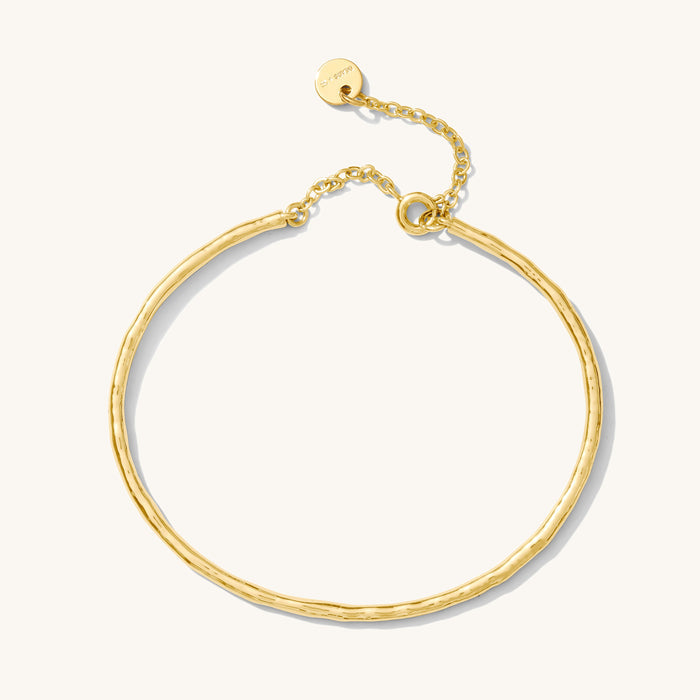 Close up of a gold bangle on a white background