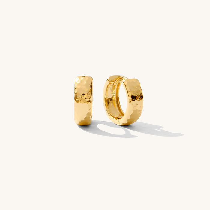 Close up of textured gold earrings on a white background