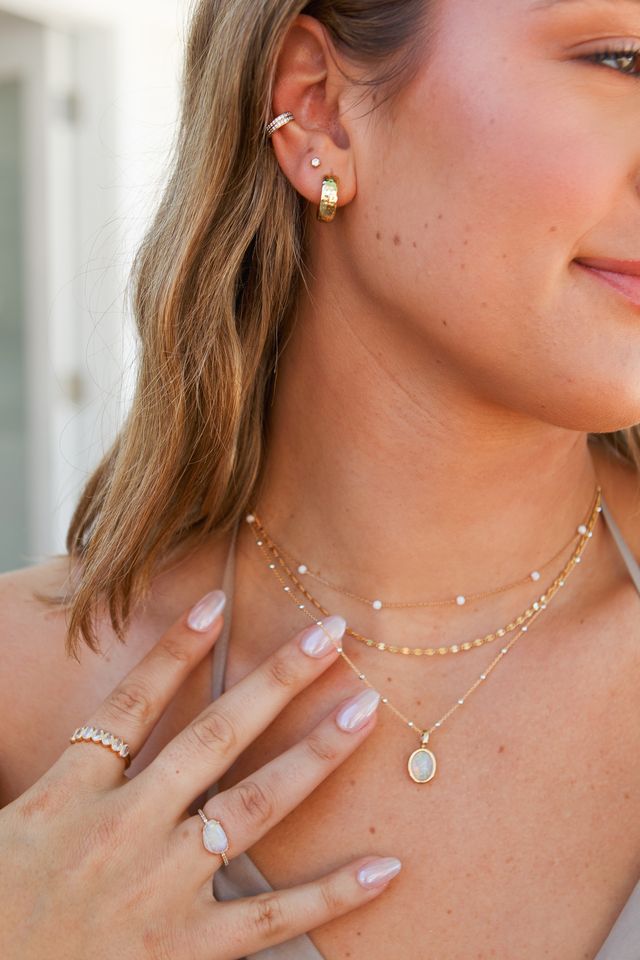 A woman wearing dainty necklaces, earrings, and rings