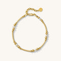 Close up of a gold bracelet with pearl accents on a white background