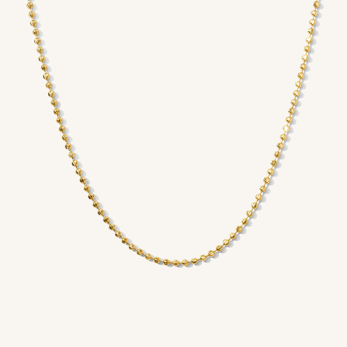 Close up of the gold Harley ball chain necklace on a white background