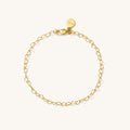 Close up of a gold heart chain bracelet on a white background