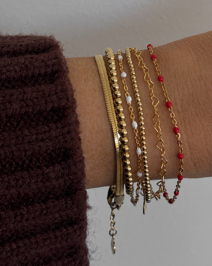 Close up of a wrist with a brown sweater and assorted gold and bead bracelets