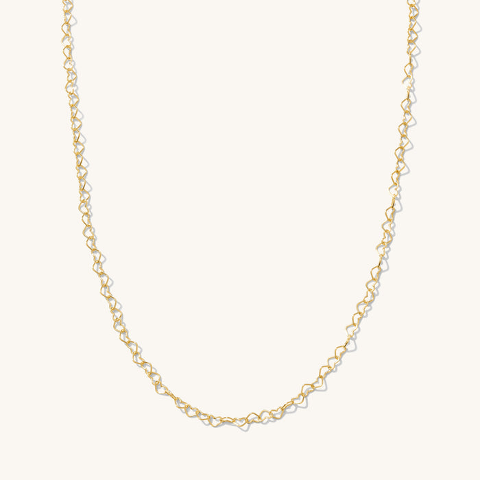 Close up of the gold Heartstring necklace on a white background