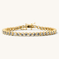 Close up of a gold bracelet with stones on a white background