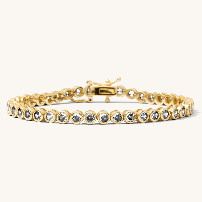 Close up of a gold bracelet with stones on a white background