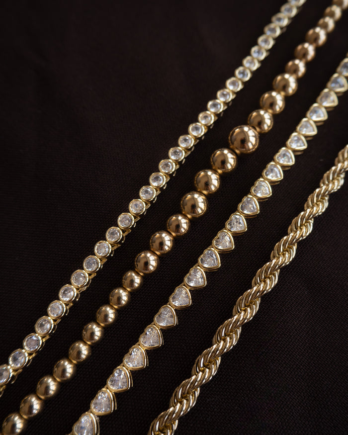 Close up of gold and stone bracelets on a maroon background
