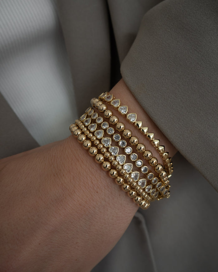 Close up of a person wearing a grey blazer and gold bracelets