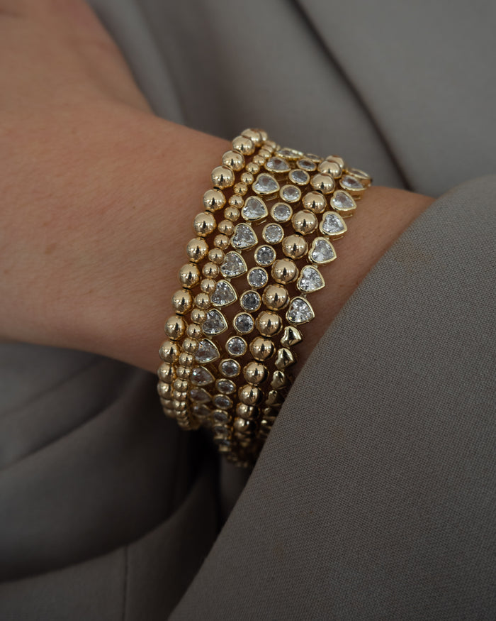 Close up of a person wearing a grey blazer and gold bracelets