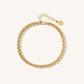 Close up of a gold curb chain bracelet on a white background