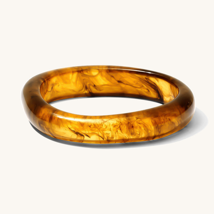 Close up of brown resin bangle on a white background