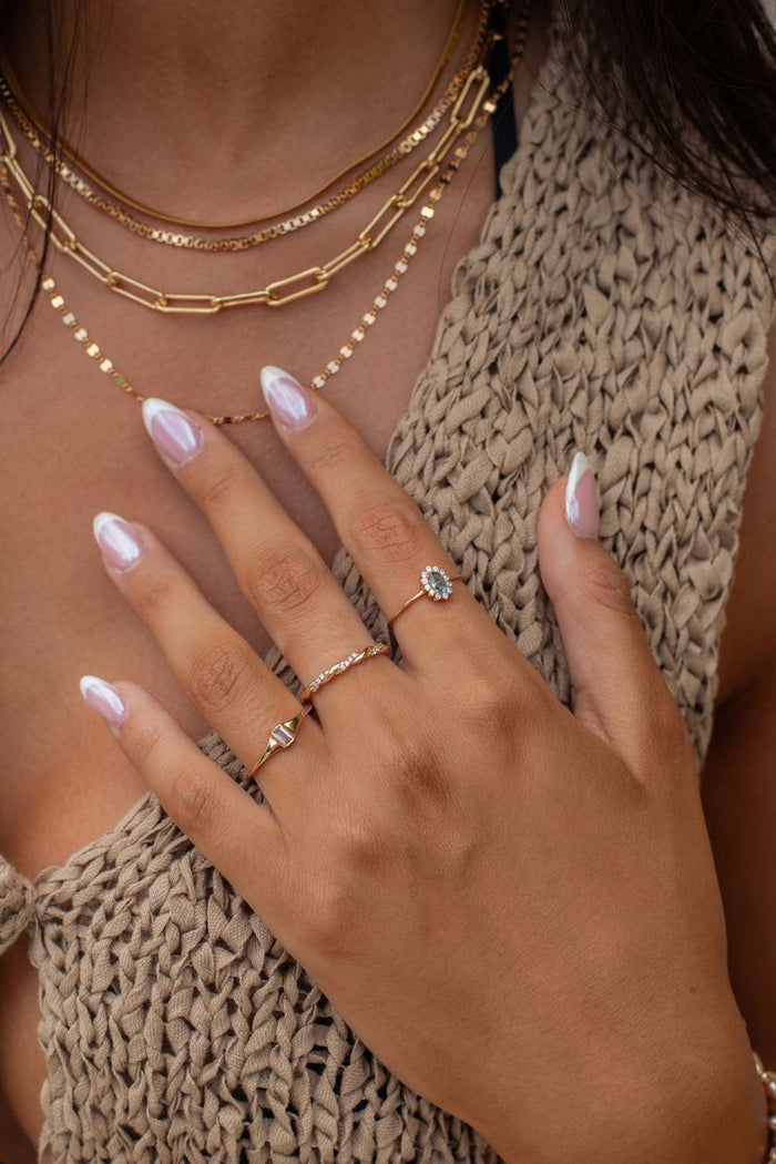 The gold Infinity Twist ring, a minimal stacking band with crystal accents