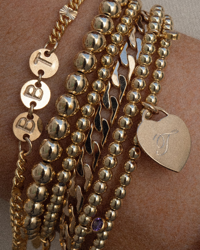 Close up of a wrist with assorted gold bracelets