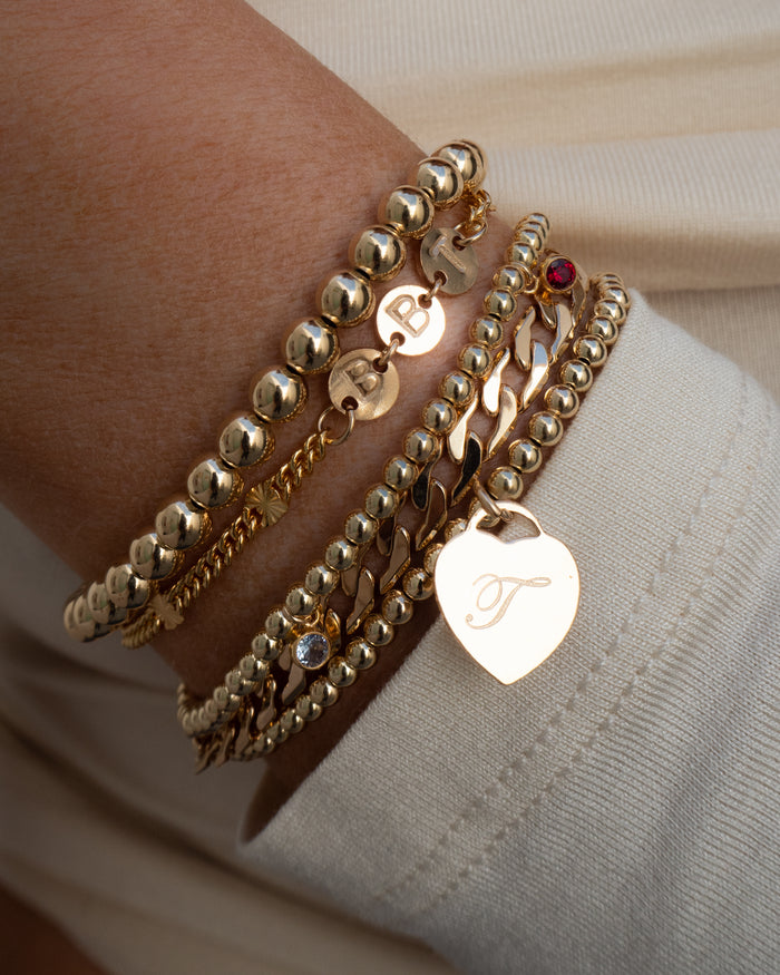 Close up of a wrist in a white sweater with assorted gold bracelets