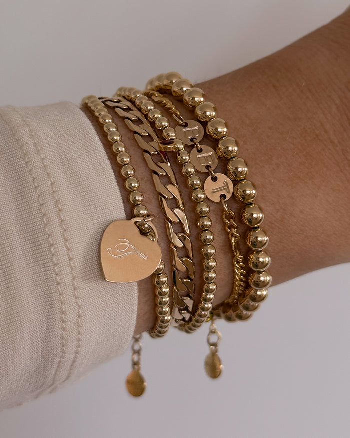 Close up of a wrist in a white sweater with assorted gold bracelets