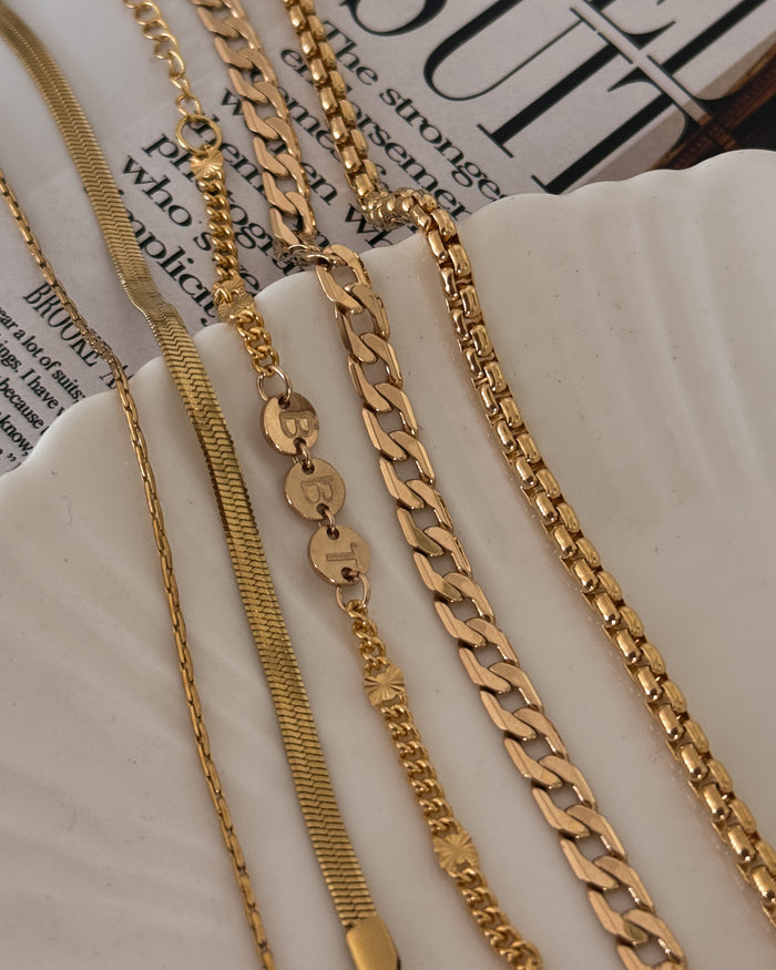 Assorted gold bracelets on a white jewelry dish