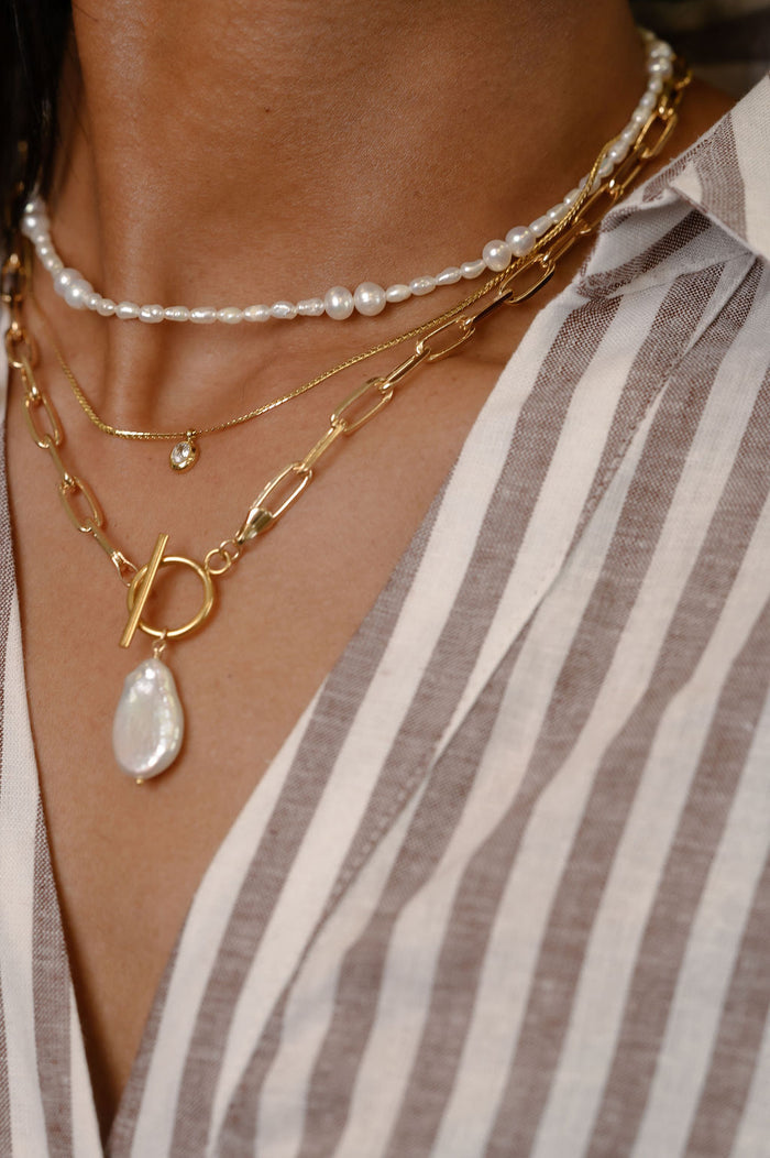 Detail view of the gold and freshwater pearl Isla necklace on a white background