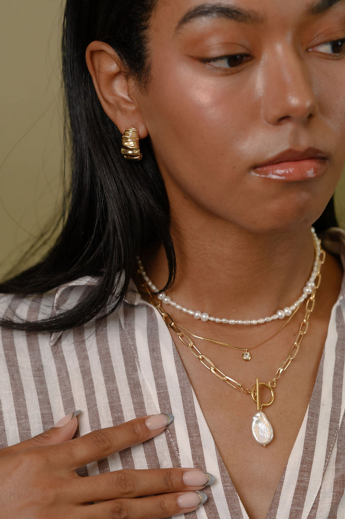 A closer look at the gold and freshwater pearl Isla necklace on a white background