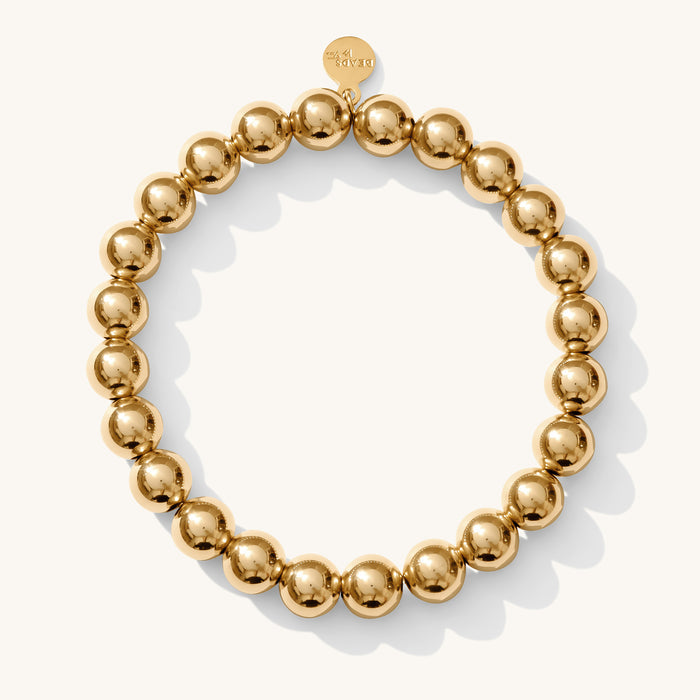 Close up of a gold bead bracelet on a white background