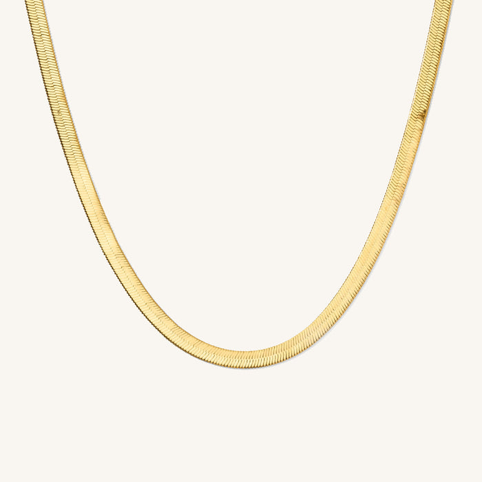 Close up of the gold Jumbo Nile herringbone necklace on a white background