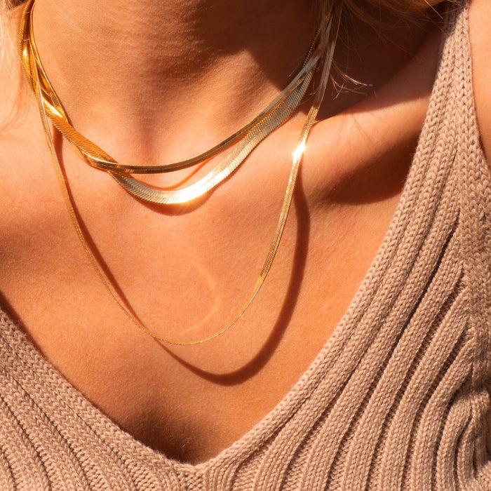Jumbo Nile necklace worn layered with other gold chains on the neckline