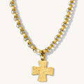 Close up of the antique gold Kaye cross necklace on a white background