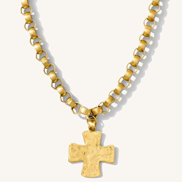 Close up of the antique gold Kaye cross necklace on a white background