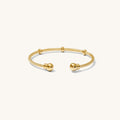 Close up of a gold cuff bracelet on a white background