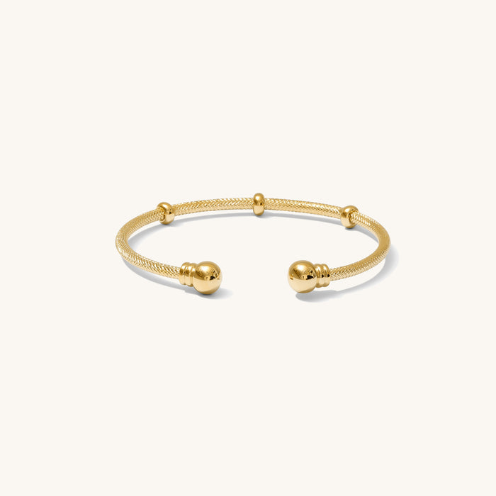 Close up of a gold cuff bracelet on a white background