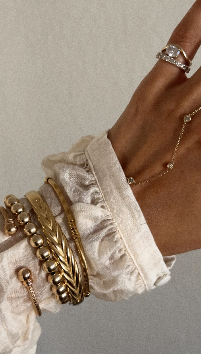 A hand with gold and stone rings and bracelets