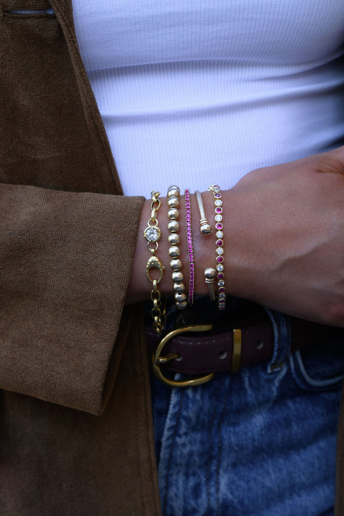 A wrist wearing multiple gold and stone bracelets