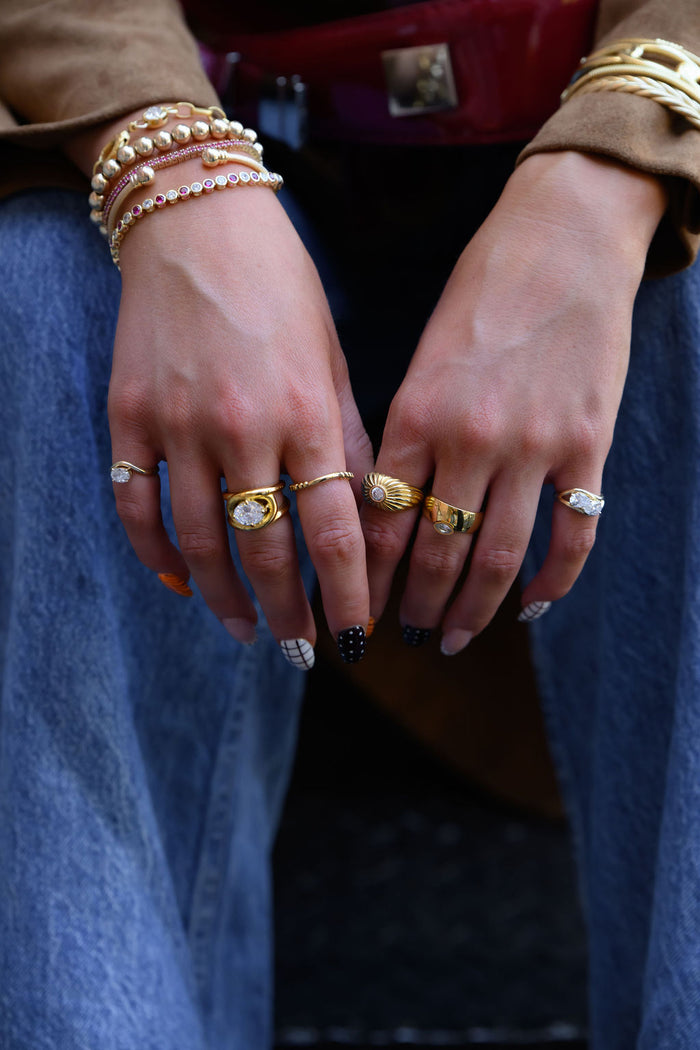 A woman's hands with various gold rings and bracelets