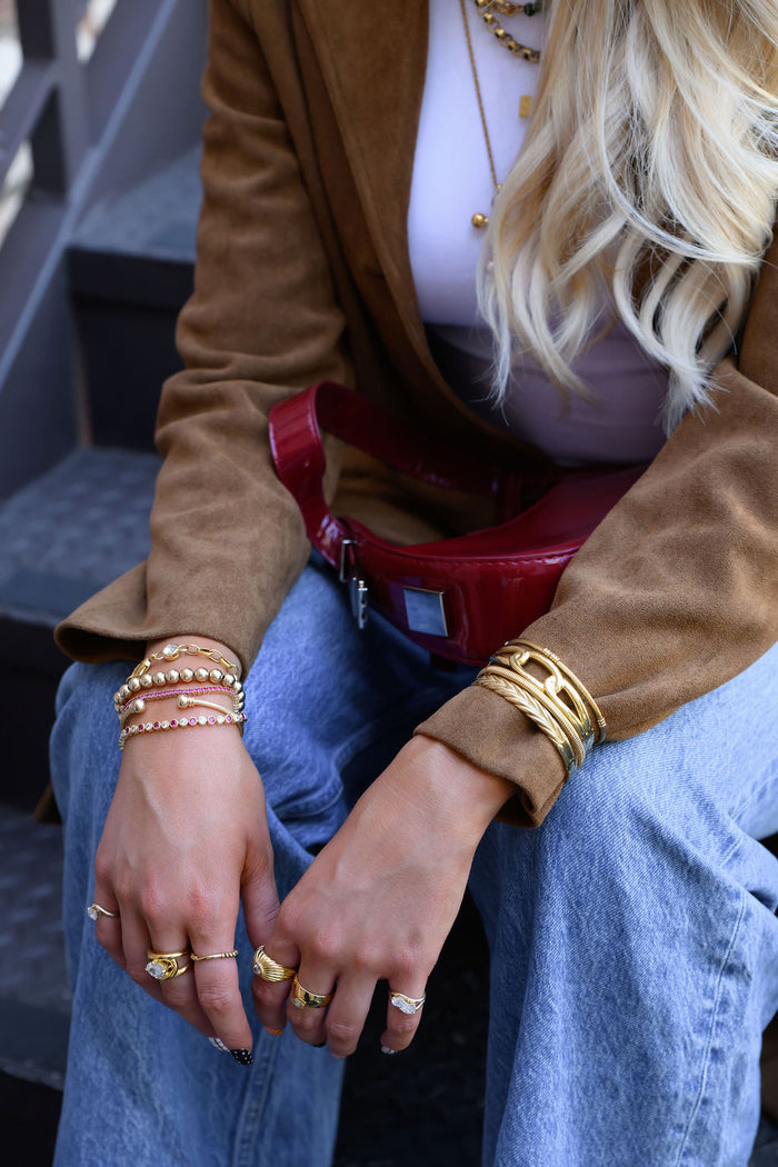 A woman wearing an outfit with blue jeans and gold jewelry