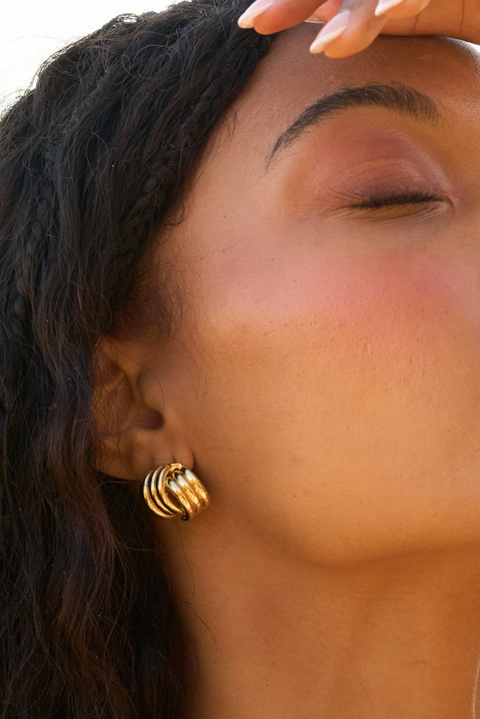 A woman with her eyes closed wearing gold earrings
