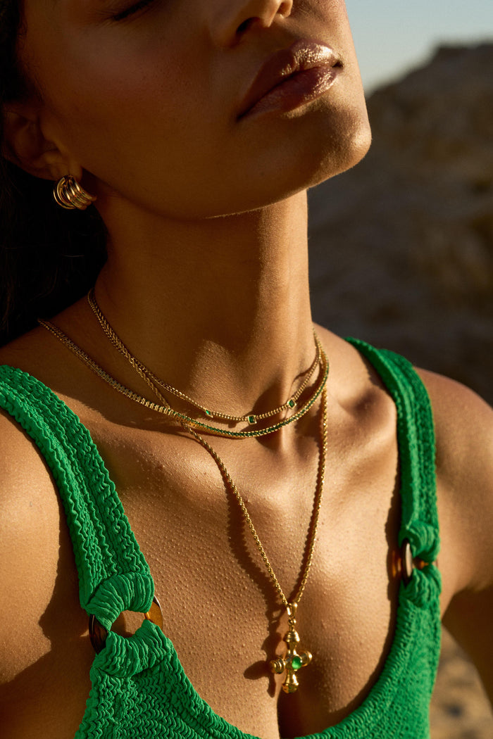A woman in a green swimsuit and gold jewelry