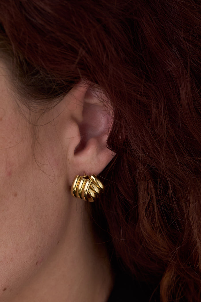 An ear with gold statement earrings