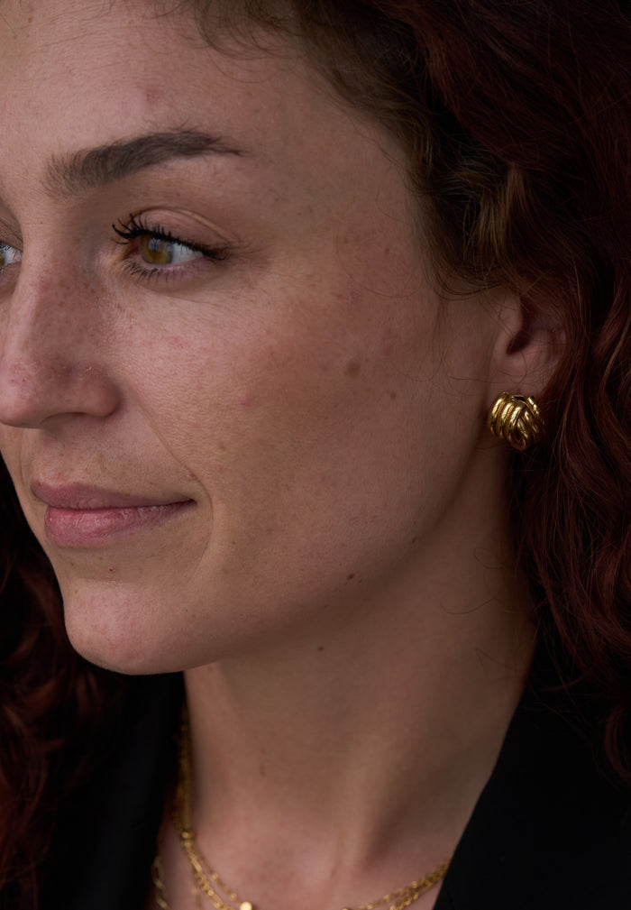 A woman wearing gold earrings