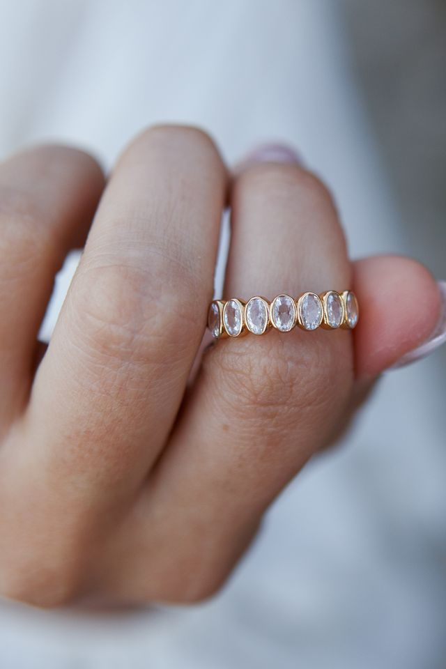 Bezel-set oval stones wrapping the top half of the Lainie eternity band