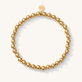 Close up of a gold bead bracelet on a white background