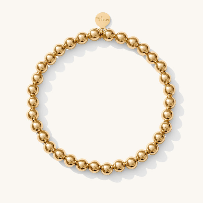 Close up of a gold bead bracelet on a white background