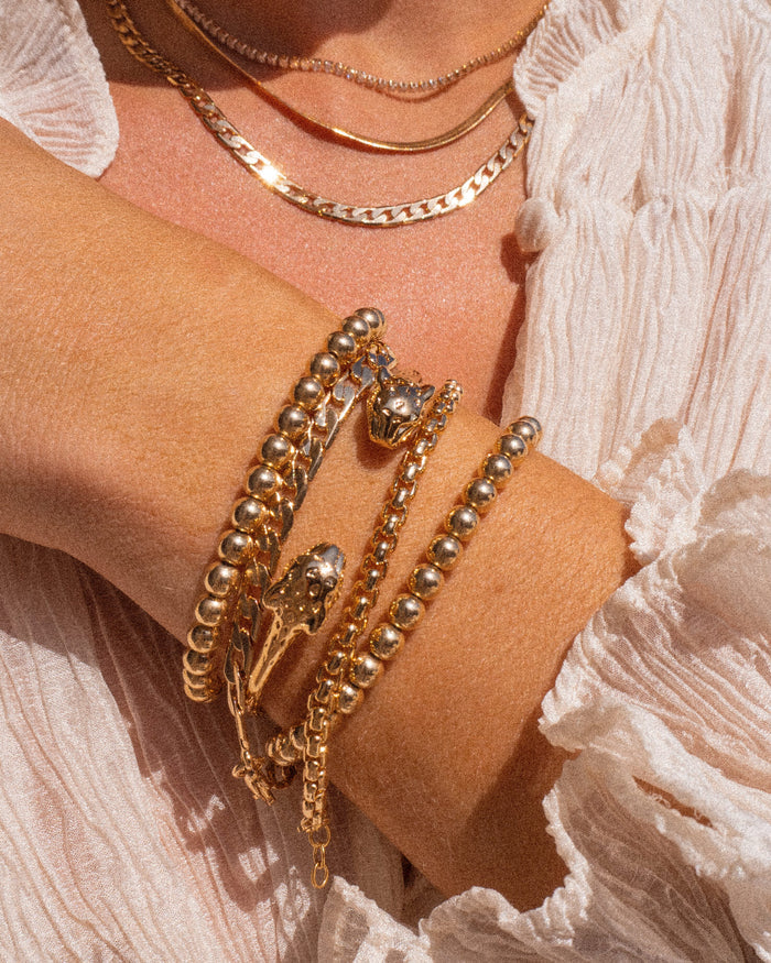Close up of a person's wrist and chest wearing a ruffled white blouse and silver bracelets
