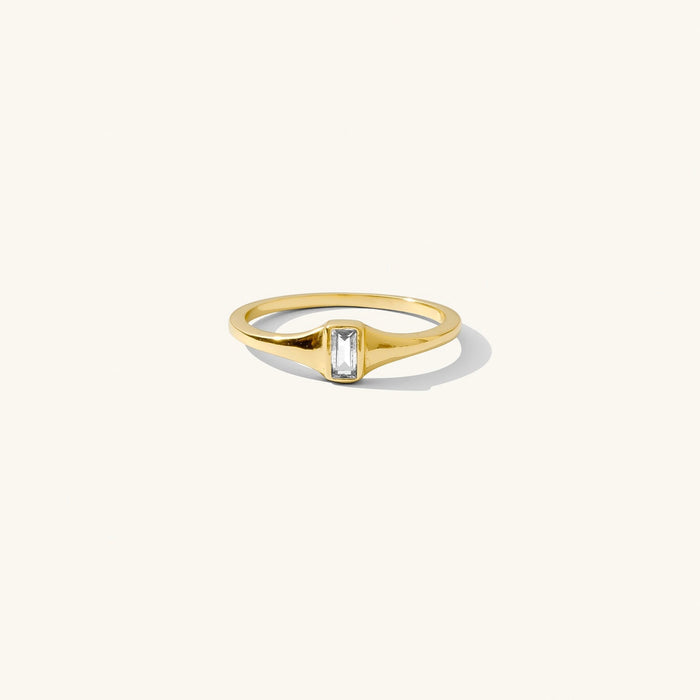 The Lina ring, a thin signet band with a bezel-set clear topaz stone