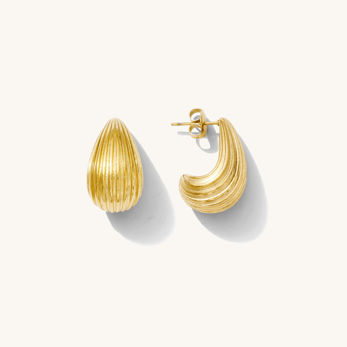 Close up of gold drop earrings on a white background
