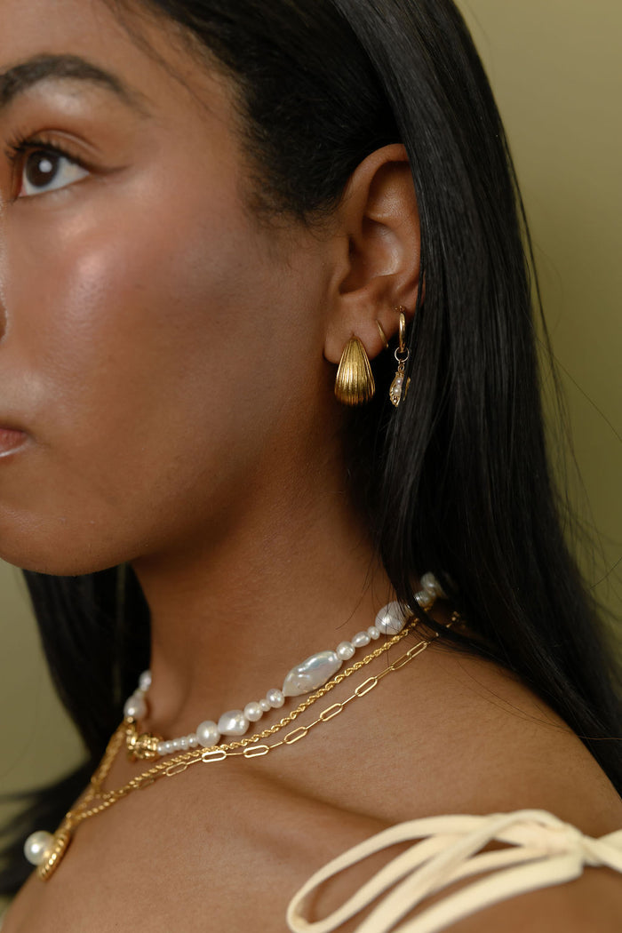 Close up of the gold Linea drop earrings on a white background