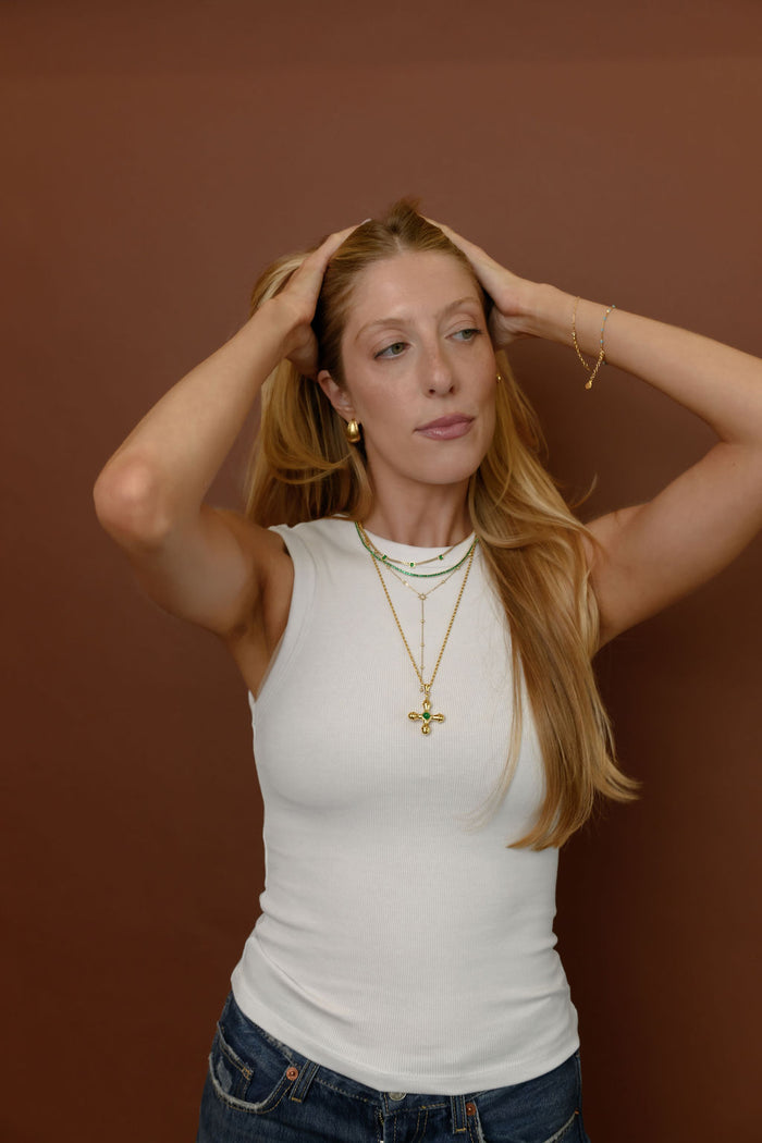 Detail view of the gold Linea drop earrings on a white background