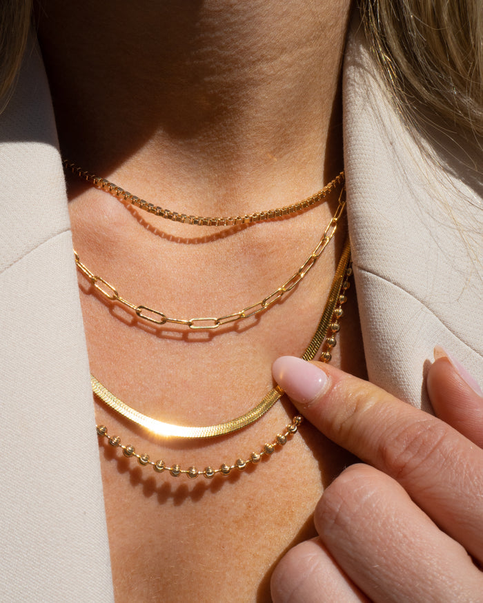 Model wearing the gold Link Up chain necklace layered with dainty gold chains